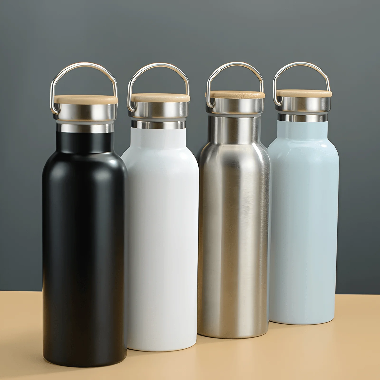Minimalist insulated stainless steel water bottle with handle lid, reusable thermos bottle on a clean desk setup with books and picture frame in background.