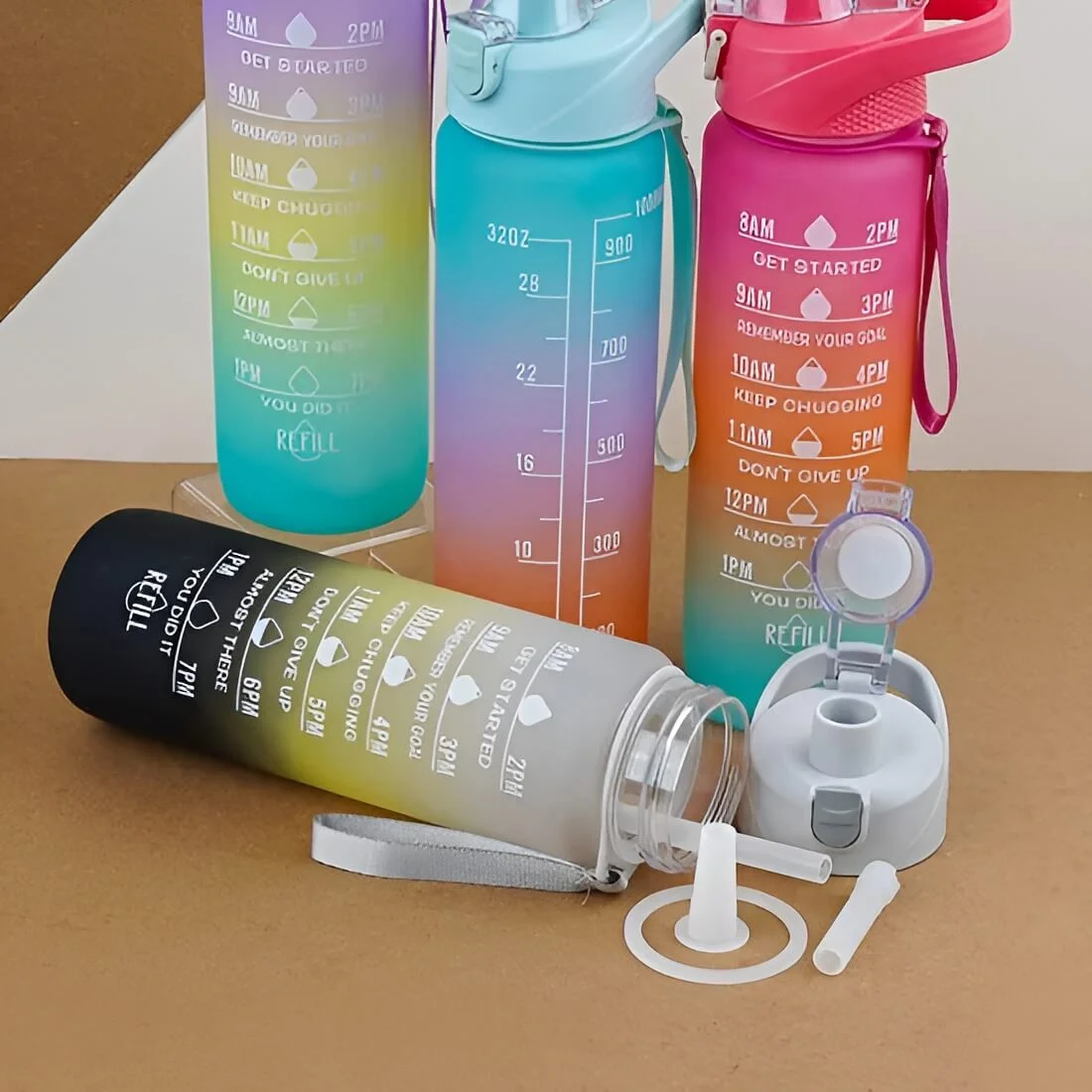 Colorful gradient motivational water bottles with time markers and measurement scale, leak-proof reusable gym bottles with flip-top lids, straw caps, and carrying straps on display.